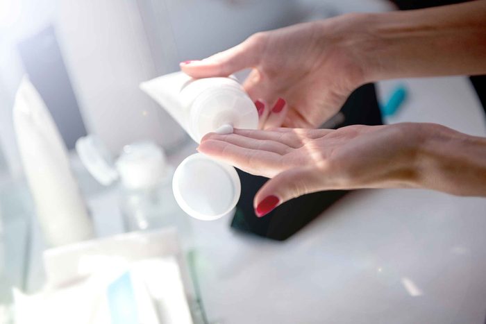 woman squeezing lotion from a tube onto her fingers