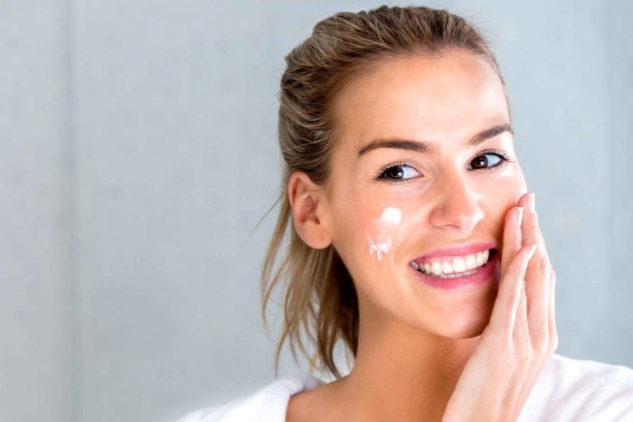 smiling woman applying face cream