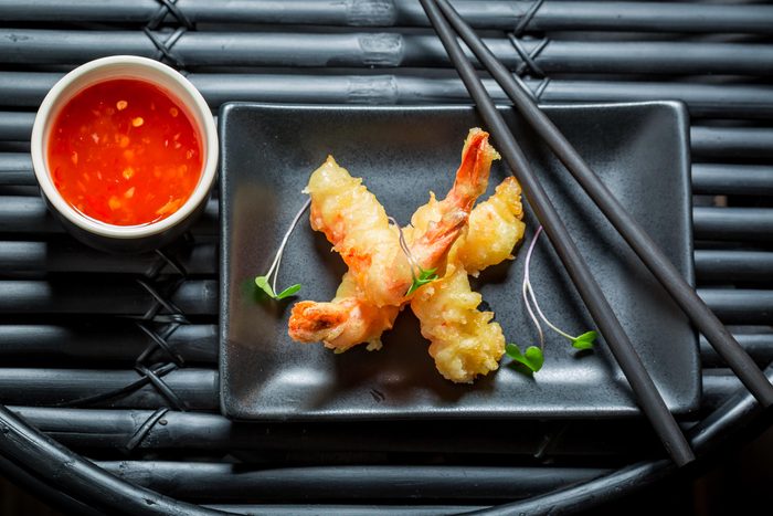 Fried shrimp tempura on a black plate.
