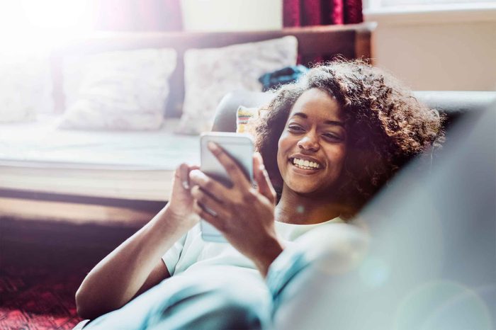 Woman lying on the couch using her cell phone.