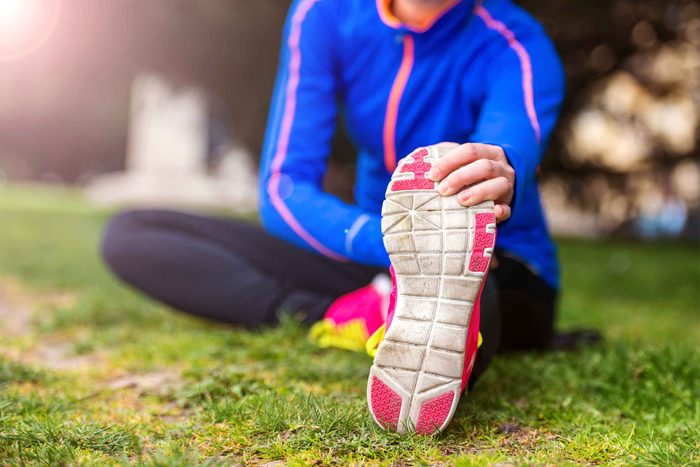 runner doing stretch on ground holding sneaker