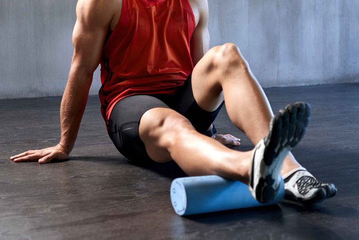 man in gym clothes using foam roller