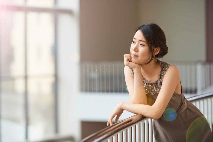 Woman in a dress leaning on a railing in a house.