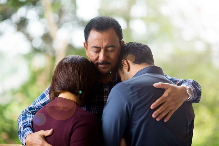 Man hugging two people outdoors.