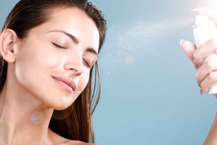 woman spraying beauty product on her face