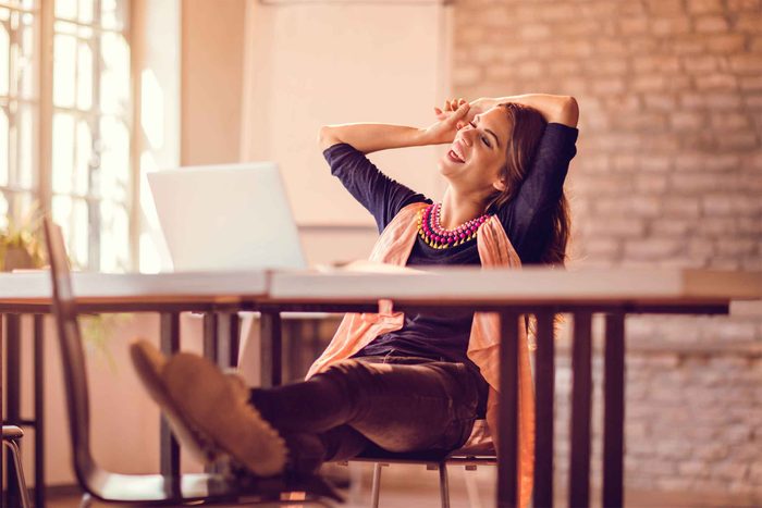 smiling woman sitting at desk with feet propped up on chair