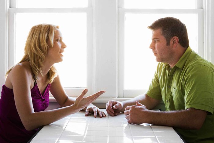 Man and woman sitting at a table talking to each other.