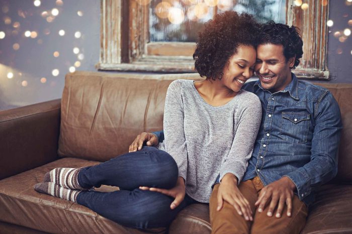 Man and woman sitting on a brown leather couch together.