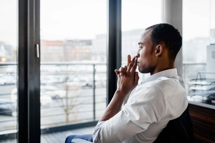 Man sitting in a chair looking thoughtfully out his patio window.