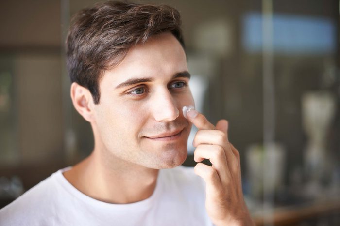 man dabbing sunscreen on cheek