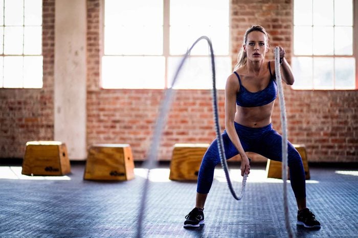 Woman doing rope wave exercises at a gym.