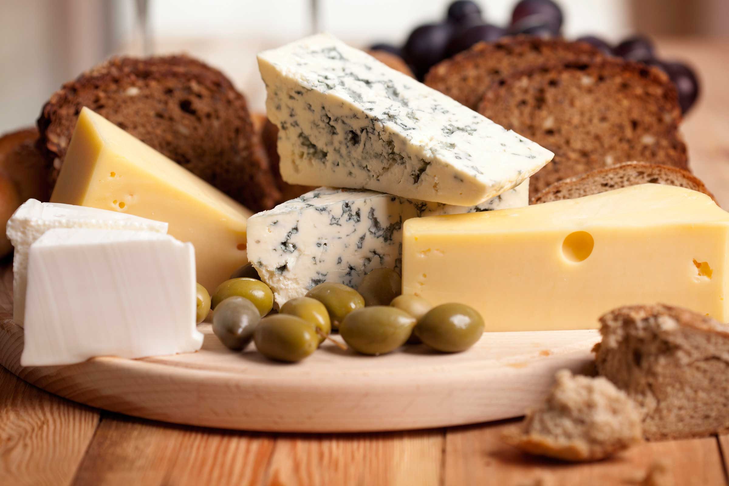 Charcuterie board of cheeses, olives, and bread.