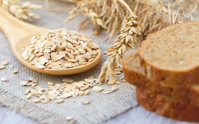 stalks of wheat, wheat kernels on a spoon, slices of brown bread