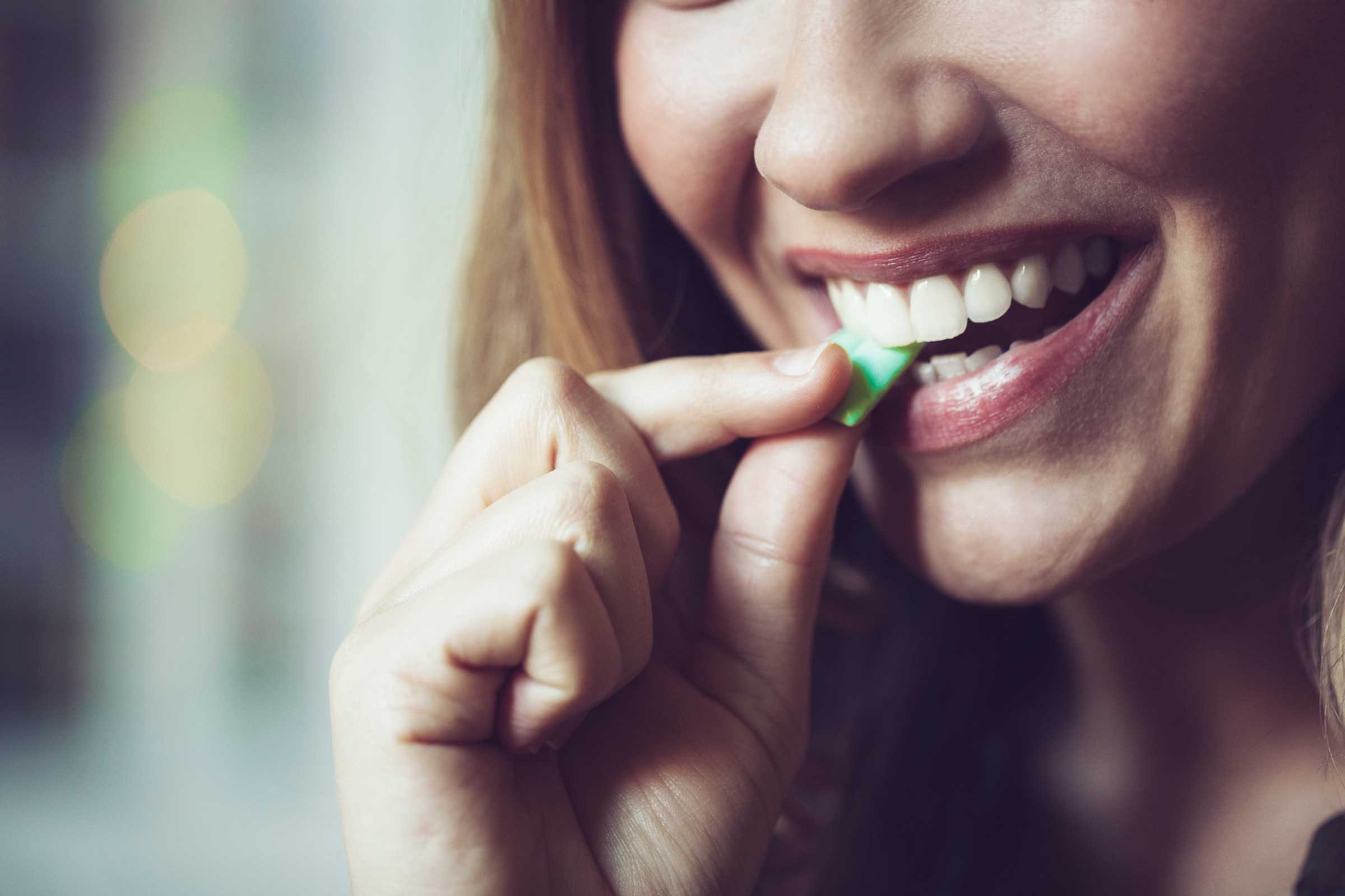 smiling woman putting a piece of gum in her mouth