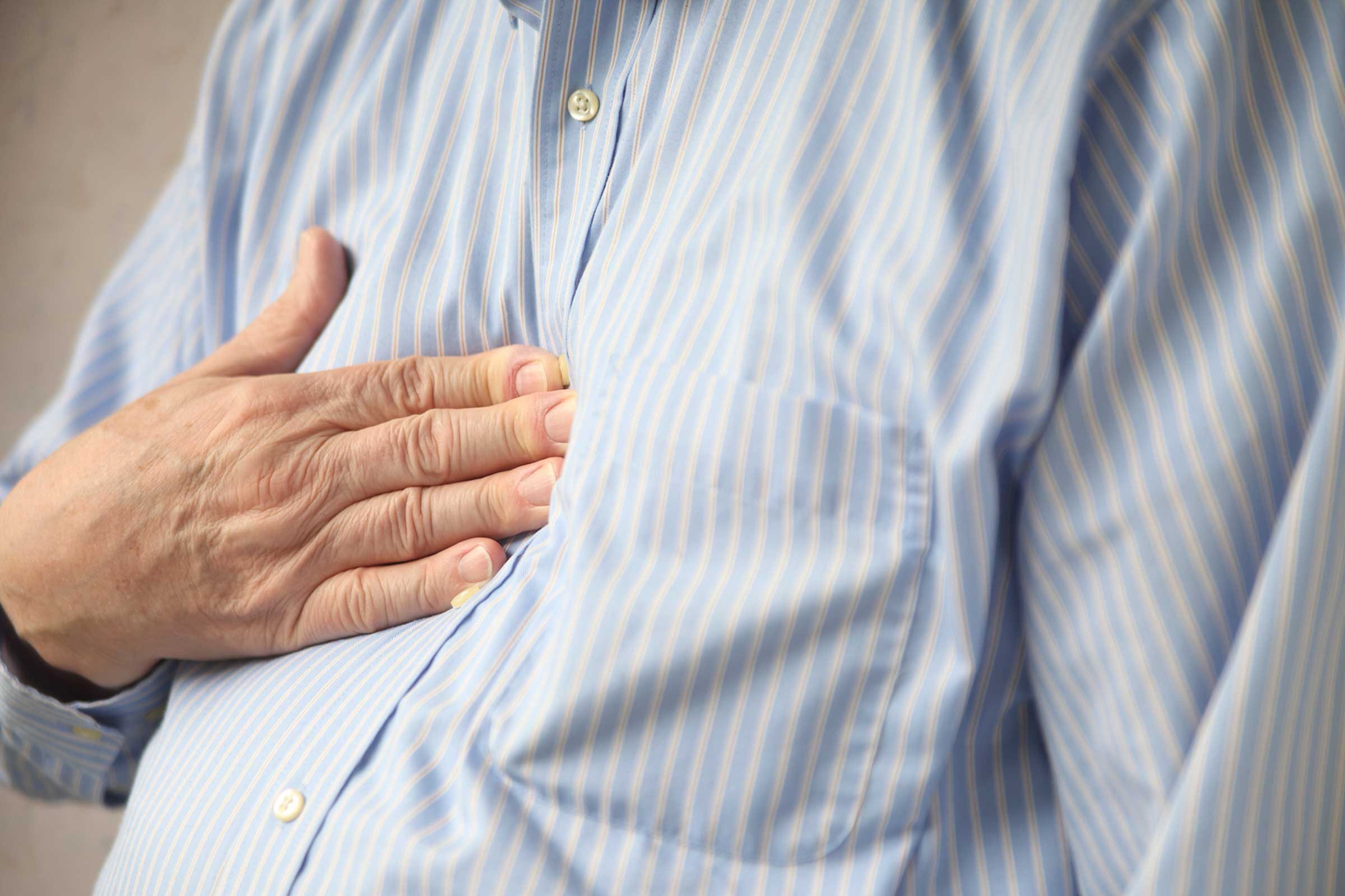 elderly man holding his hand against his chest