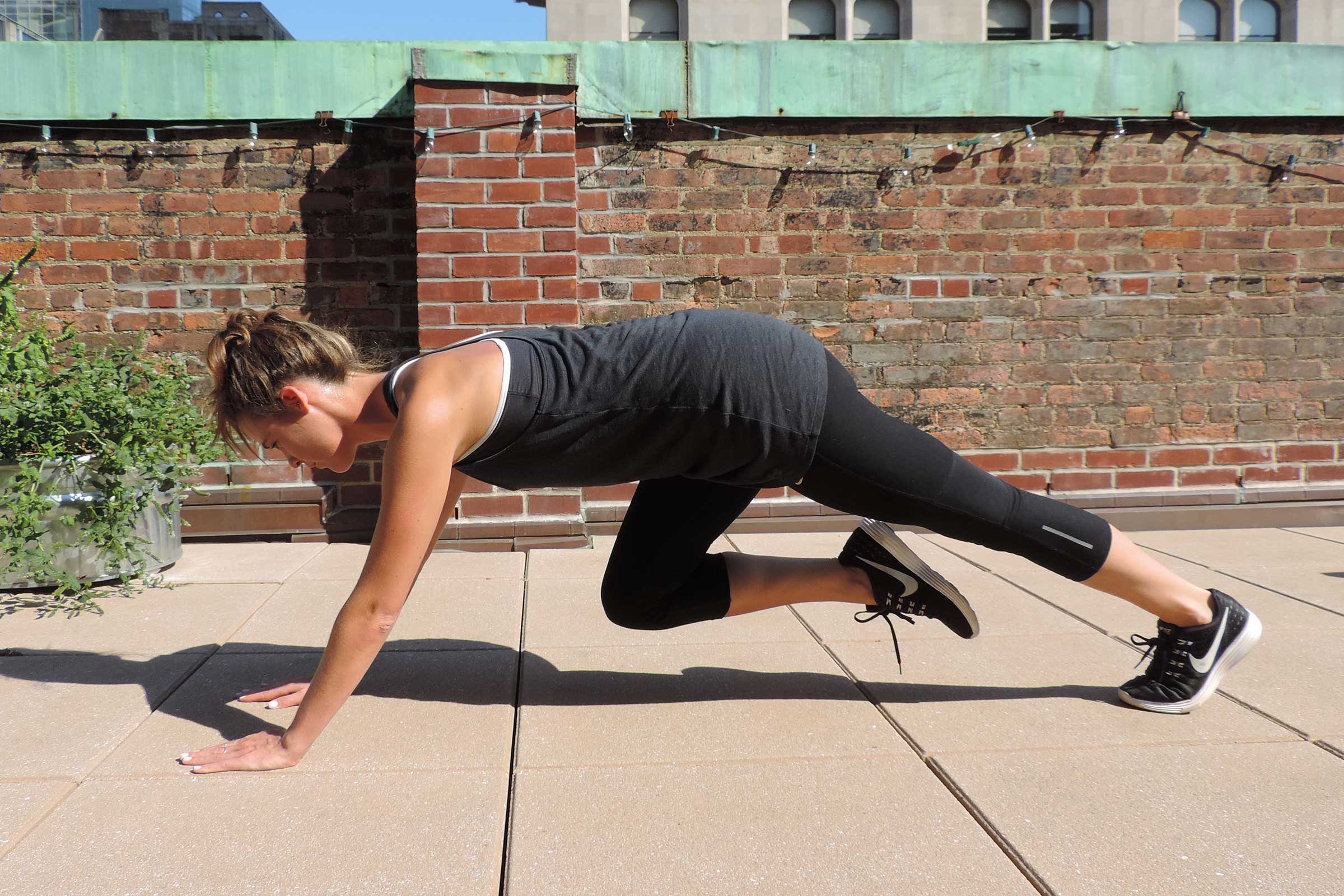 Woman in exercise gear doing mountain climber exercises.