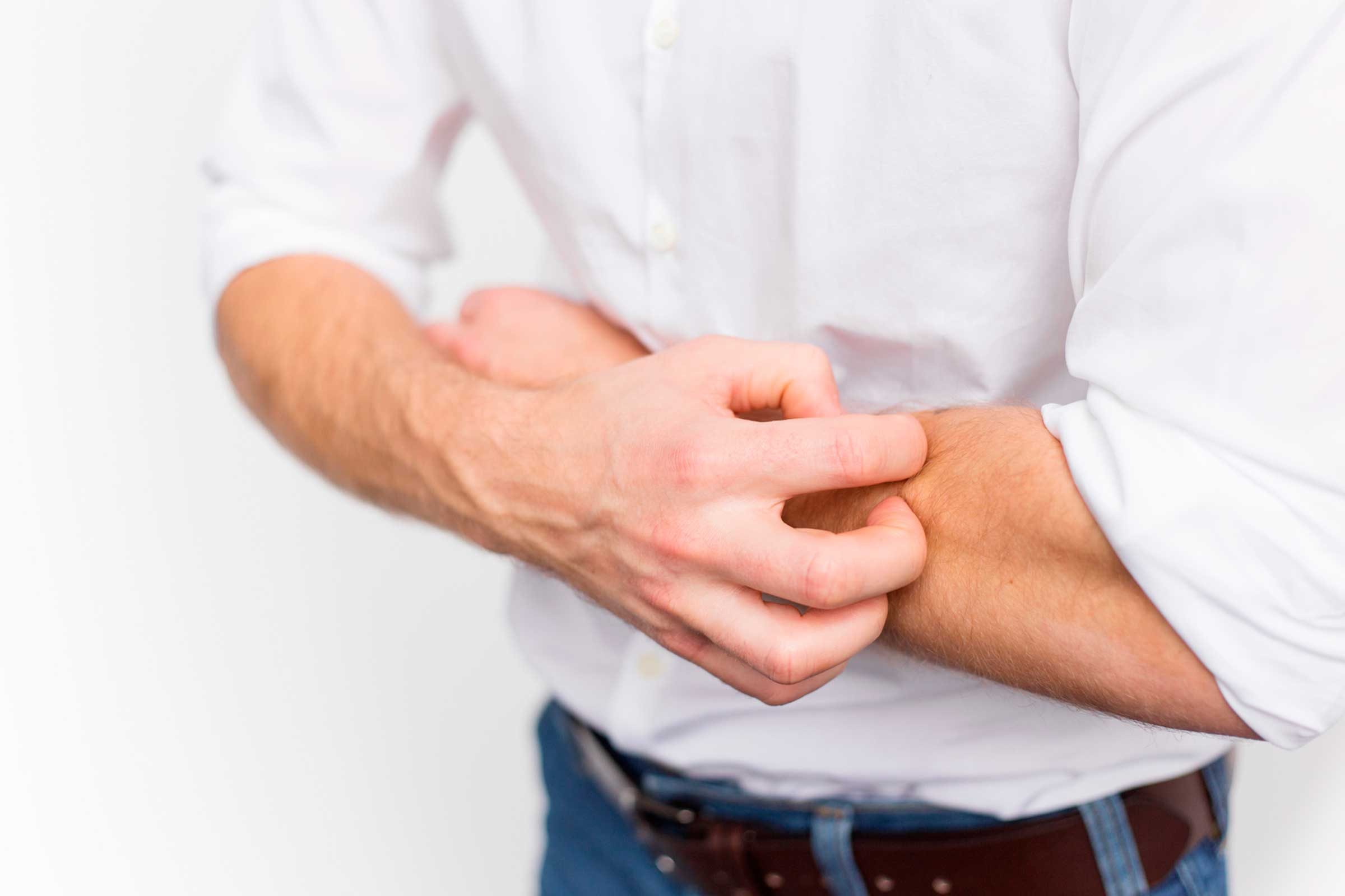 man in a white shirt scratching his forearm