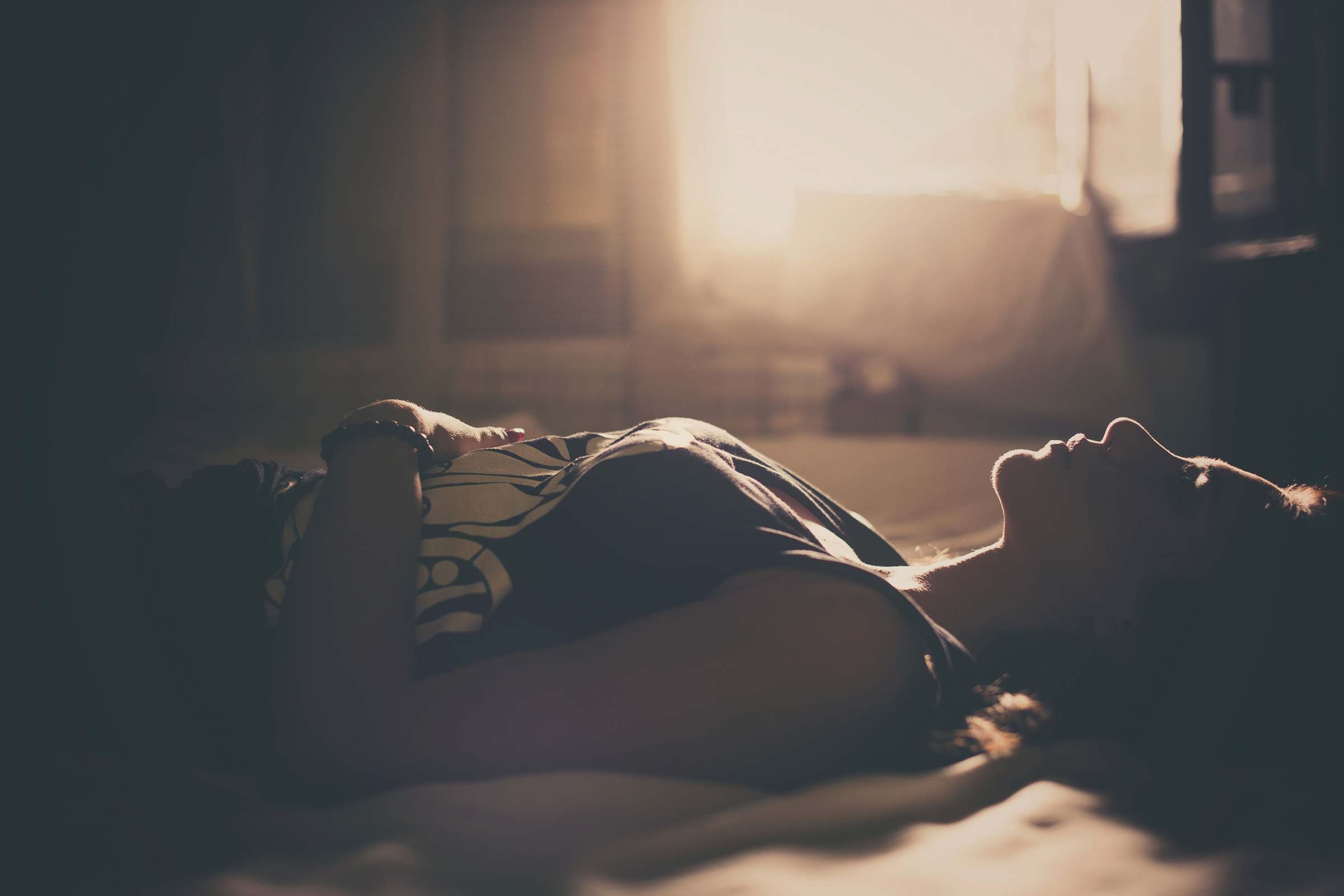 woman lying on bed in the dark