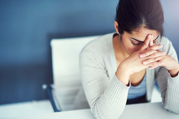 Tired woman resting her head on her hands at her desk.