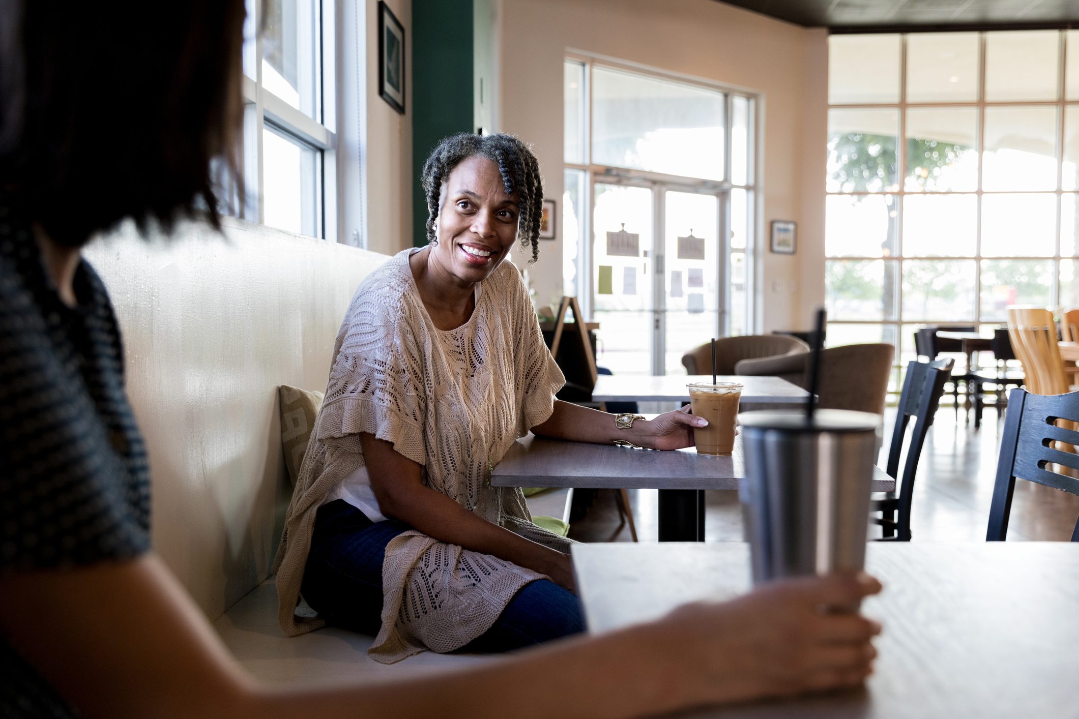 two women talking to each other in a coffee shop