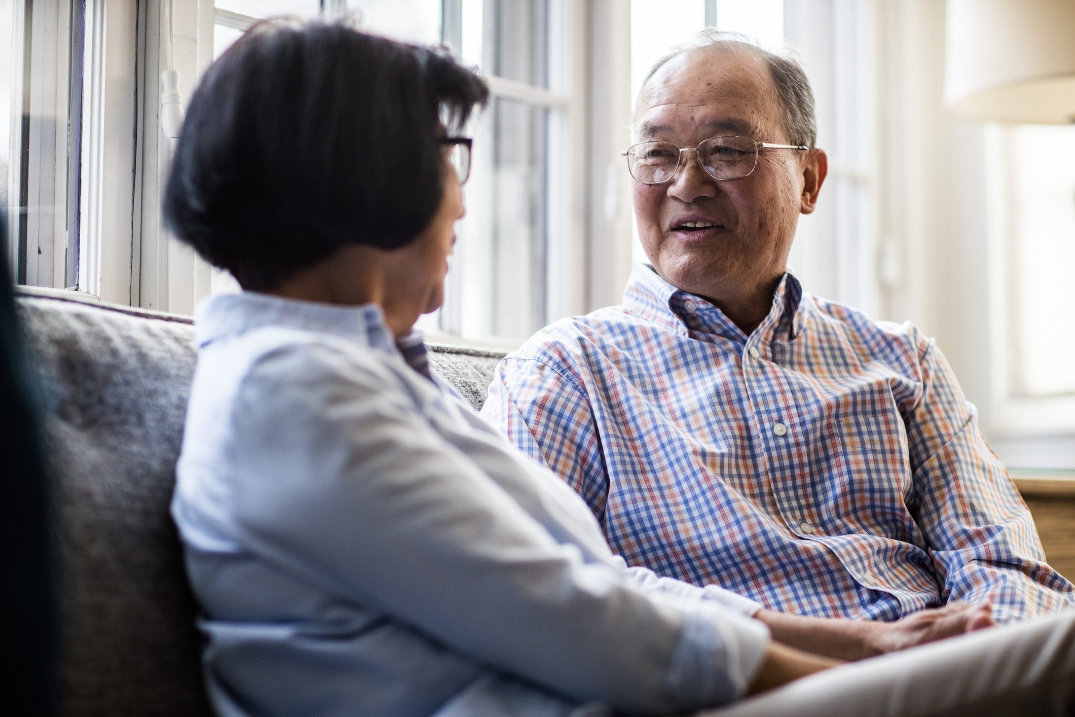 senior couple sitting on couch and talking to each other