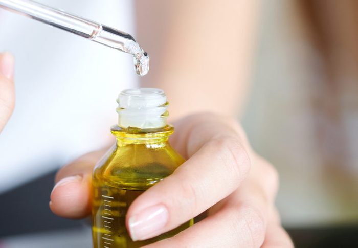 hands of a beautiful woman Dropping serum collagen moisturizer of face into clear yellow bottle soft light background. Protector skin Treatment facial essence oil, Vitamin C. Beauty and spa Con