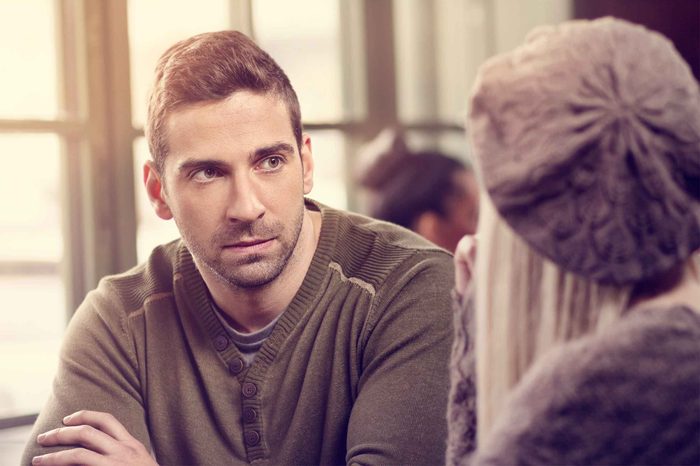 Man wearing a sweater looking at a woman wearing a cap.