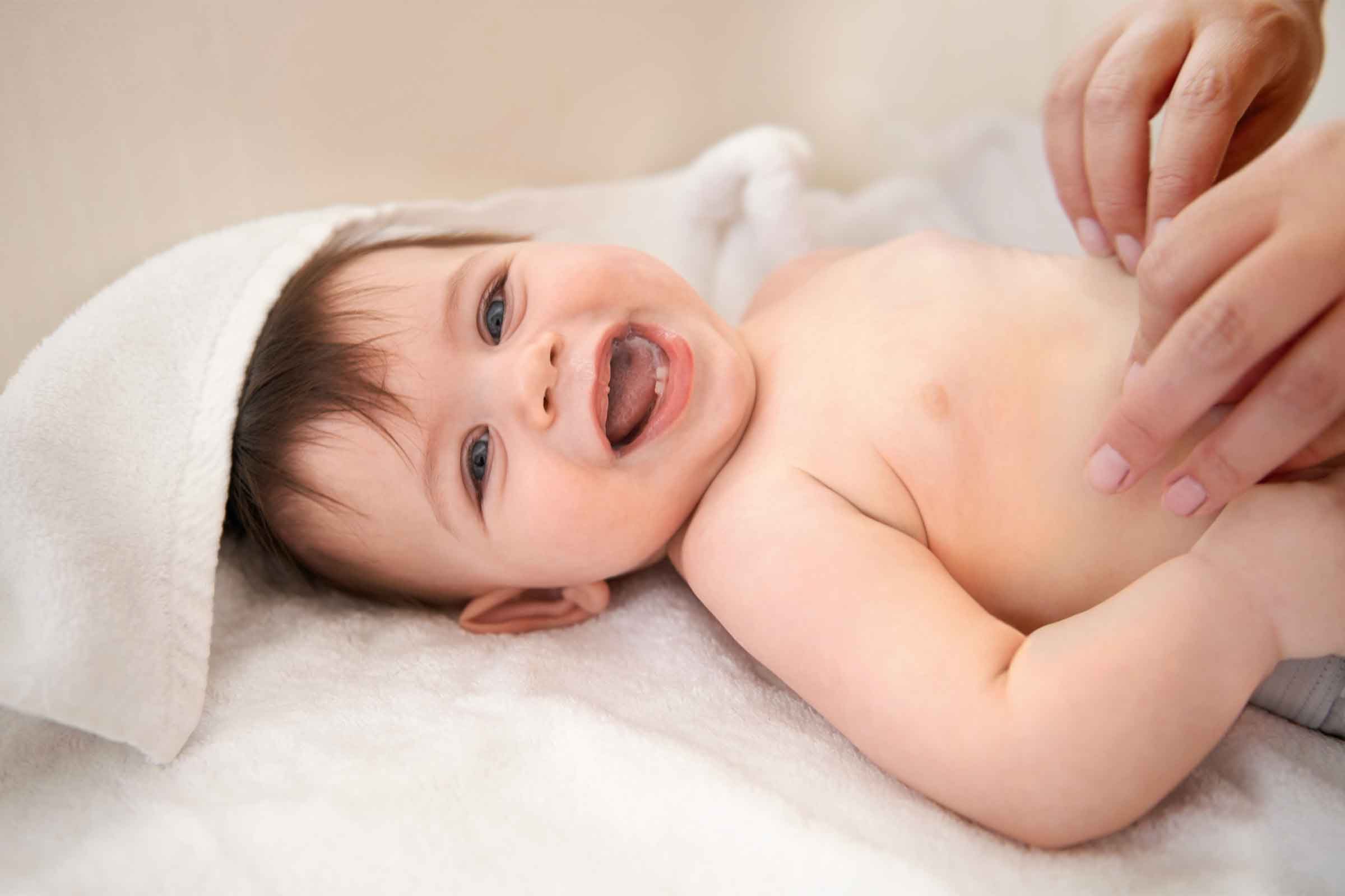 mom putting on diaper on smiling baby