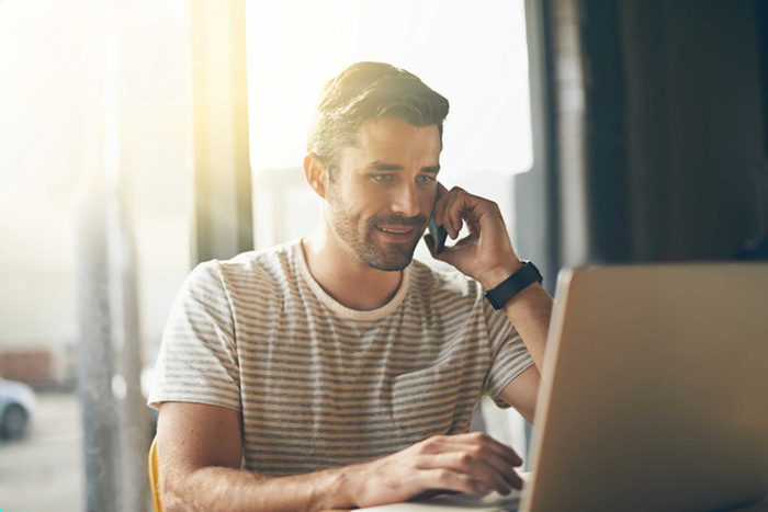 man in front of laptop talking on cell phone