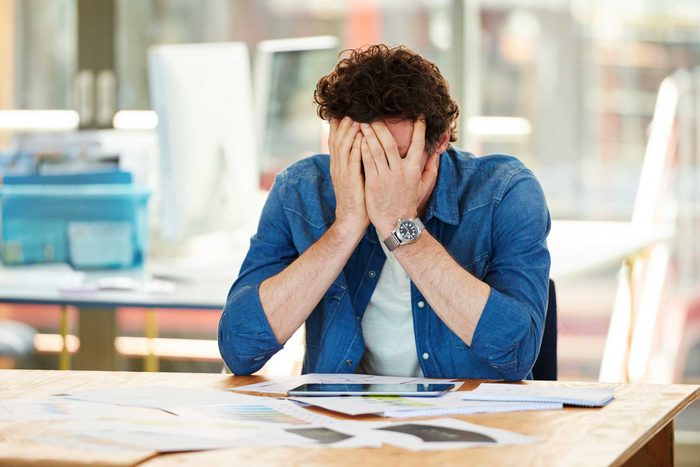 Man at a desk with his head buried in his hands.