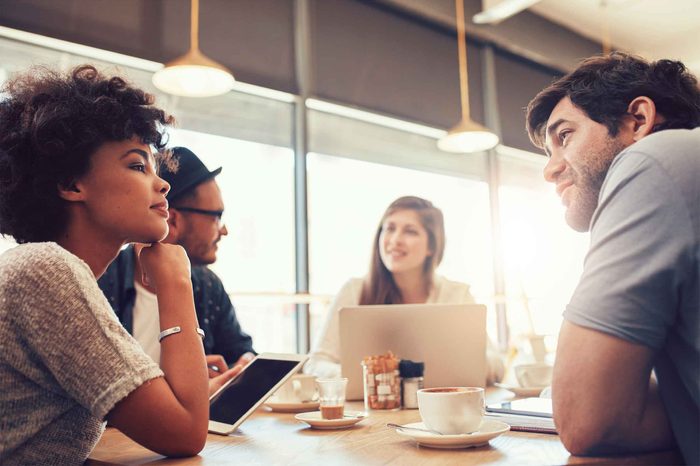 Woman sitting at a coffee table with a laptop surrounded by friends.