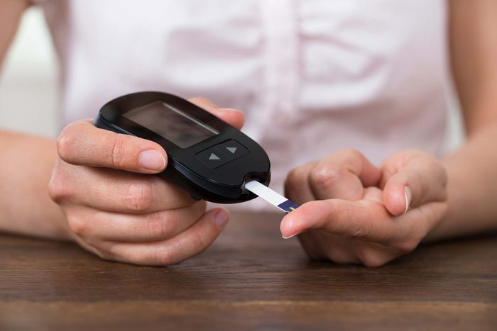 woman testing her blood sugar with finger-stick device