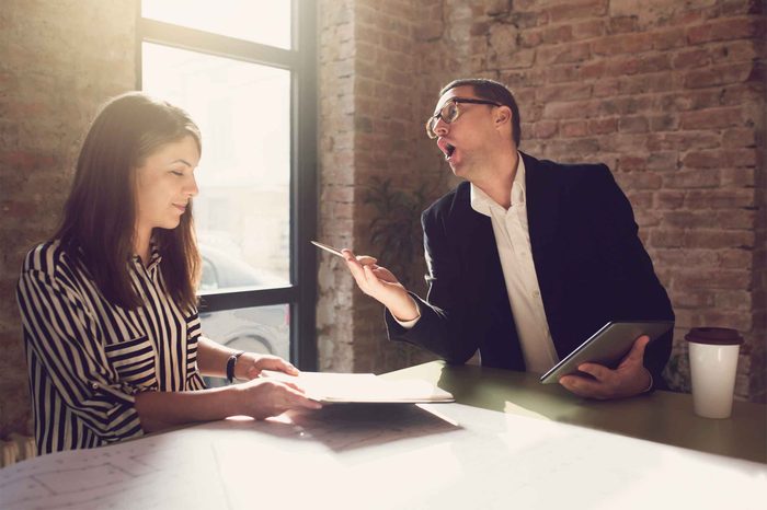 Man holding a tablet speaking to a woman who is looking at a piece of paper.