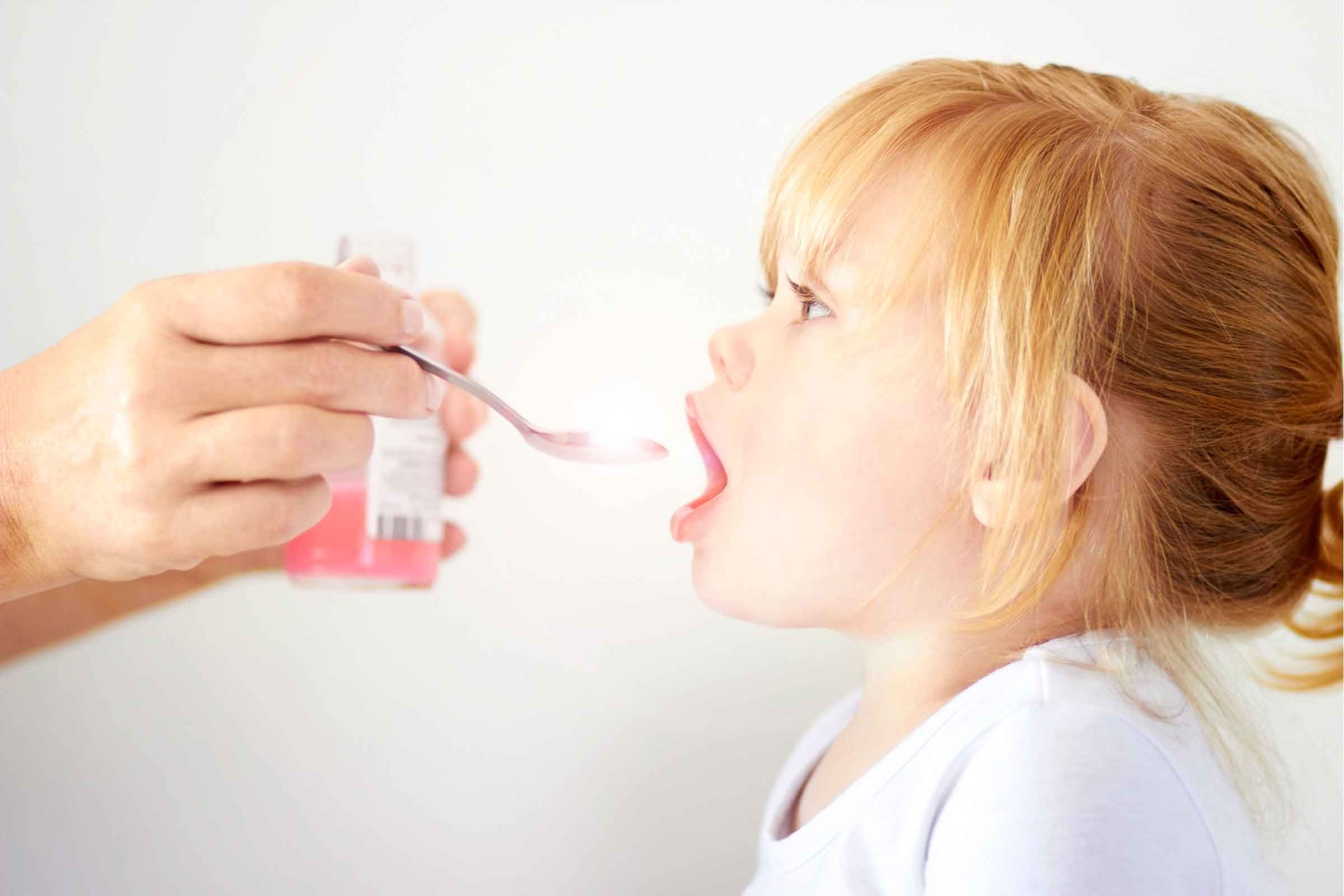 mom giving toddler girl spoonful of medicine