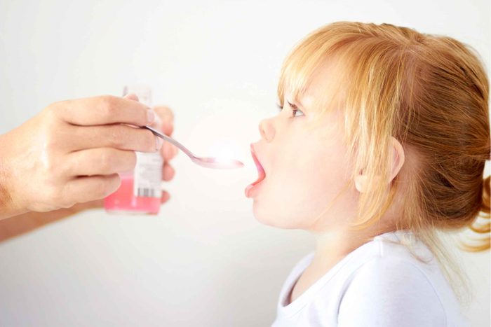 mom giving toddler girl spoonful of medicine