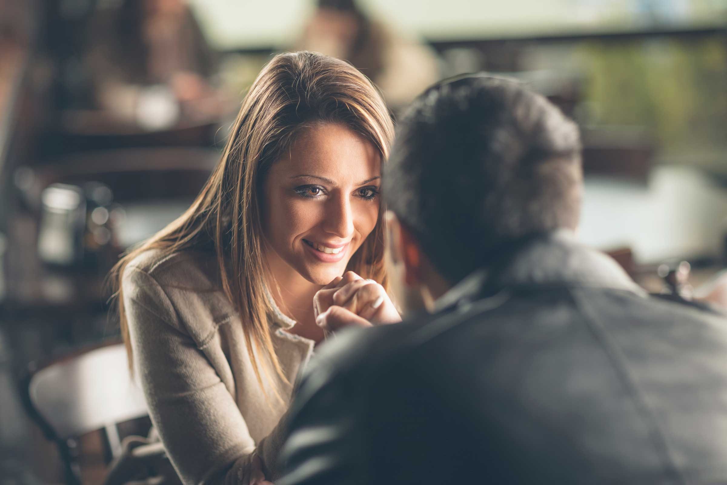 Woman smiling at man, sitting at a table