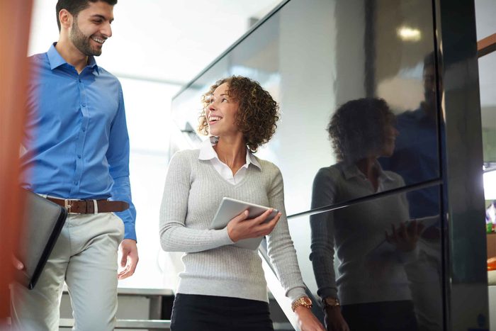 Male and female colleagues walking and talking at work