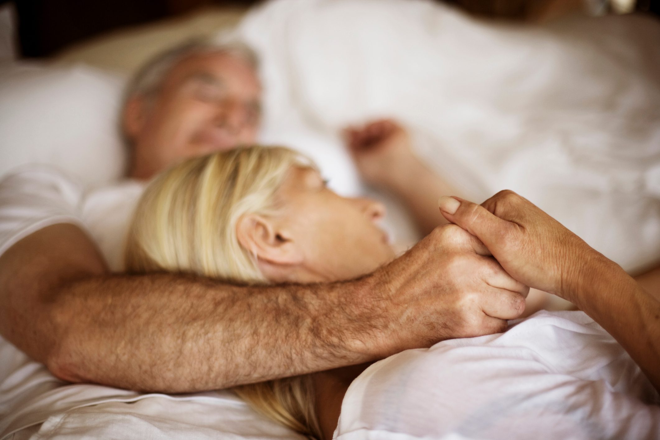 close up of couple holding hands in bed