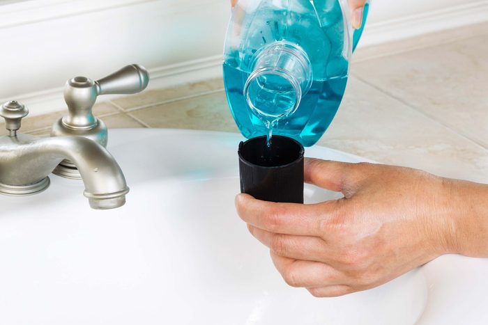 Someone pouring a capful of mouthwash.