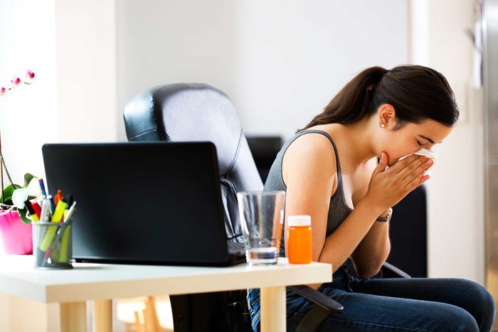 woman sneezing at her desk