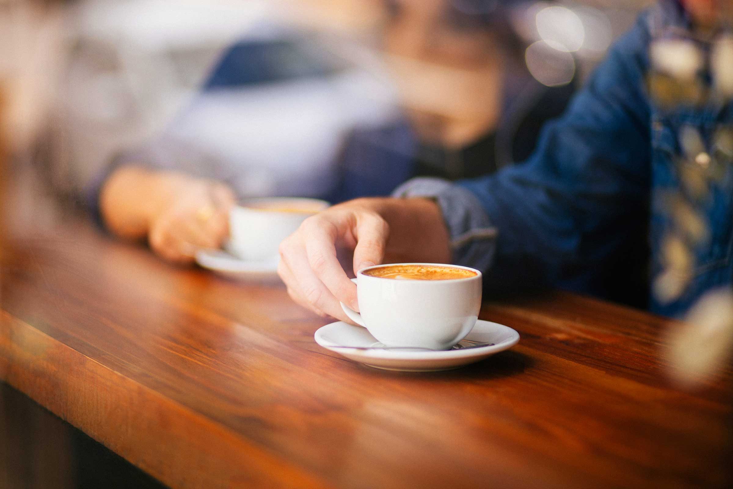 people holding cups of coffee at a counter