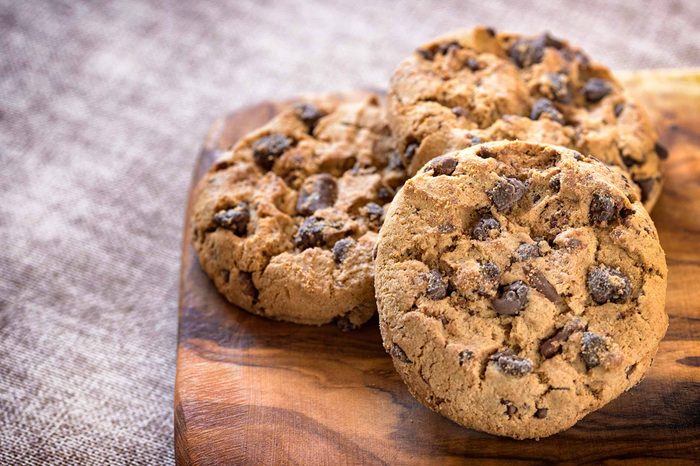 Chocolate chip cookies arranged on a wooden cutting board.