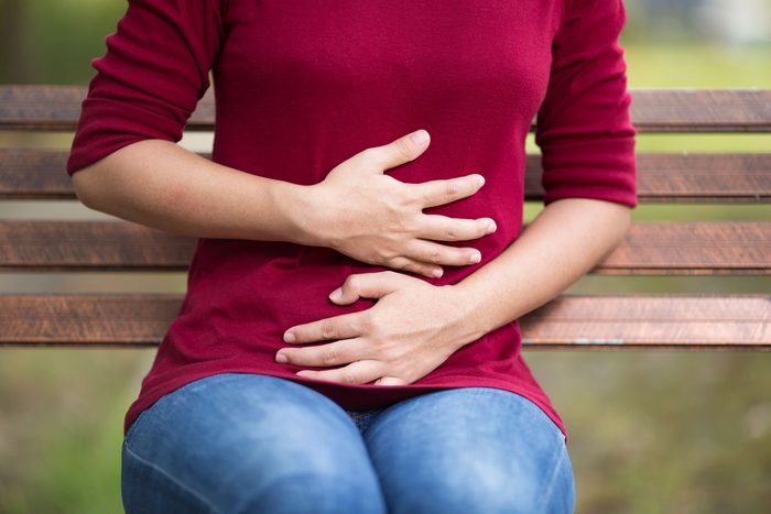 woman sitting on bench holding her stomach