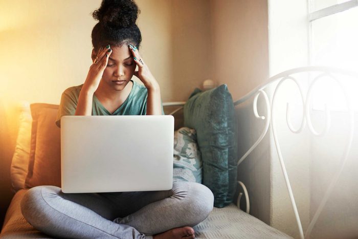 woman with laptop holding her temples