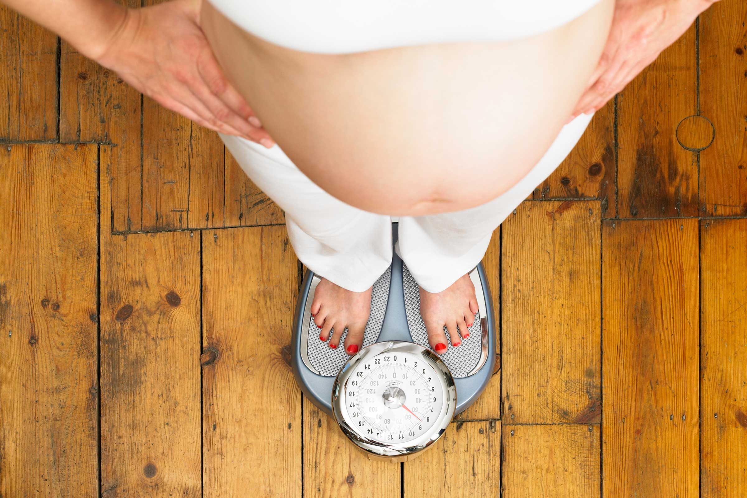 pregnant woman standing on scale