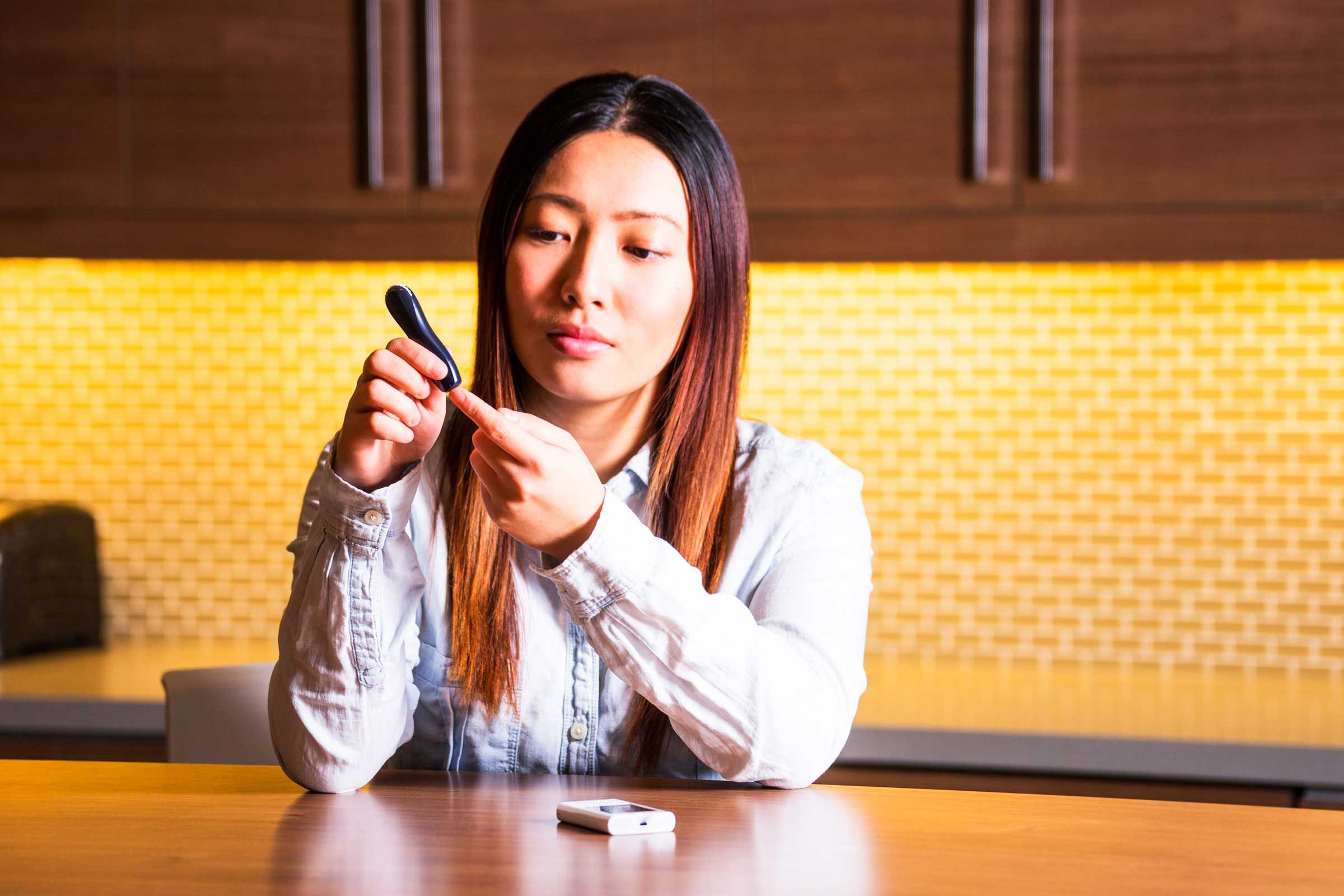 woman with glucometer testing tip of finger 