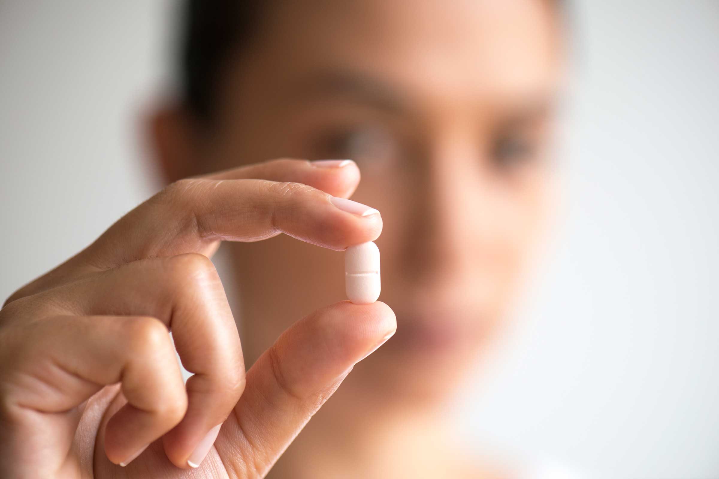 hand holding a tablet with woman's blurry face in the background