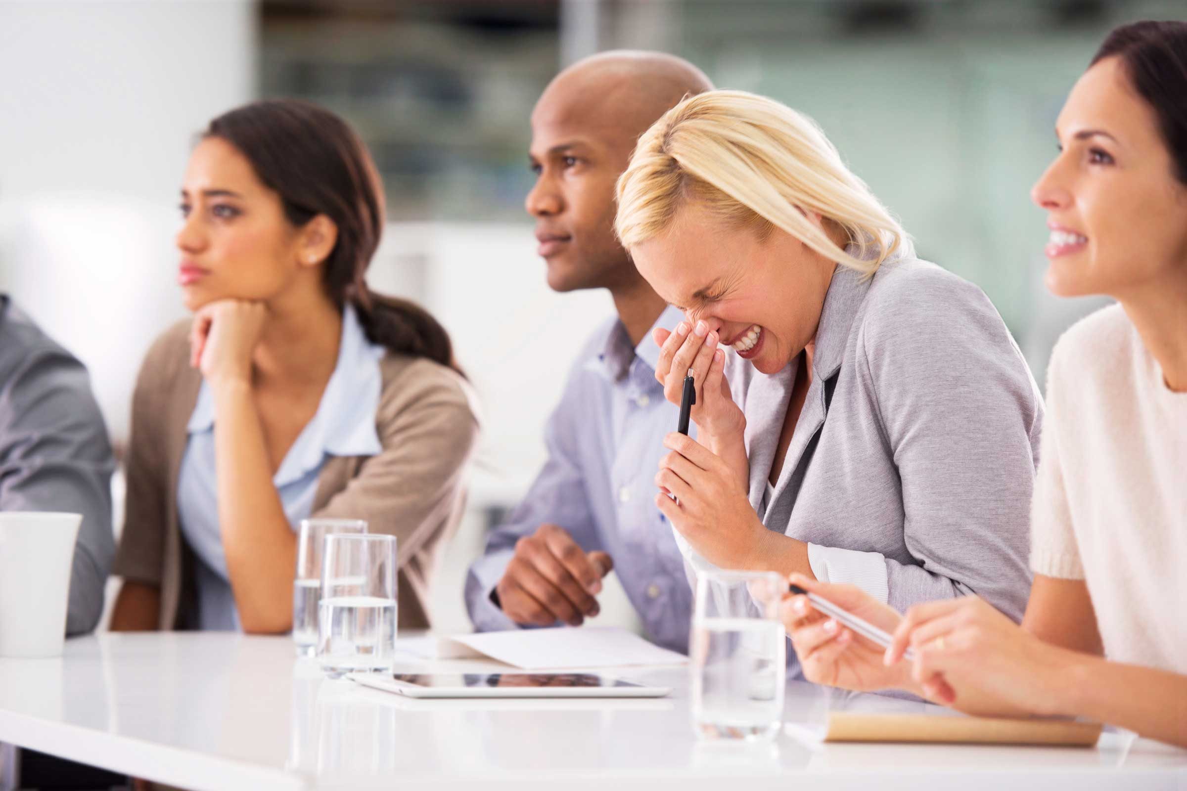 people at a table with one woman sneezing