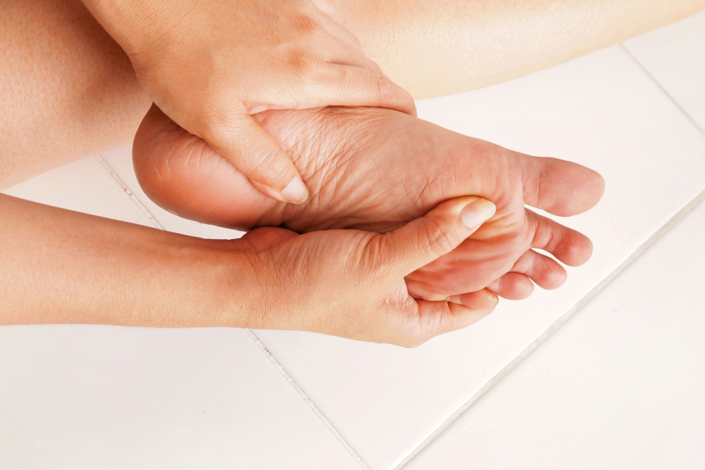 woman pressing against the arch of her foot 