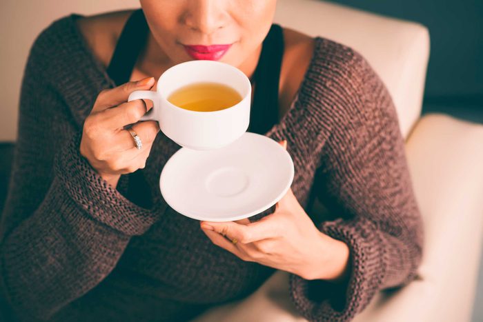 woman sitting on couch and sipping tea